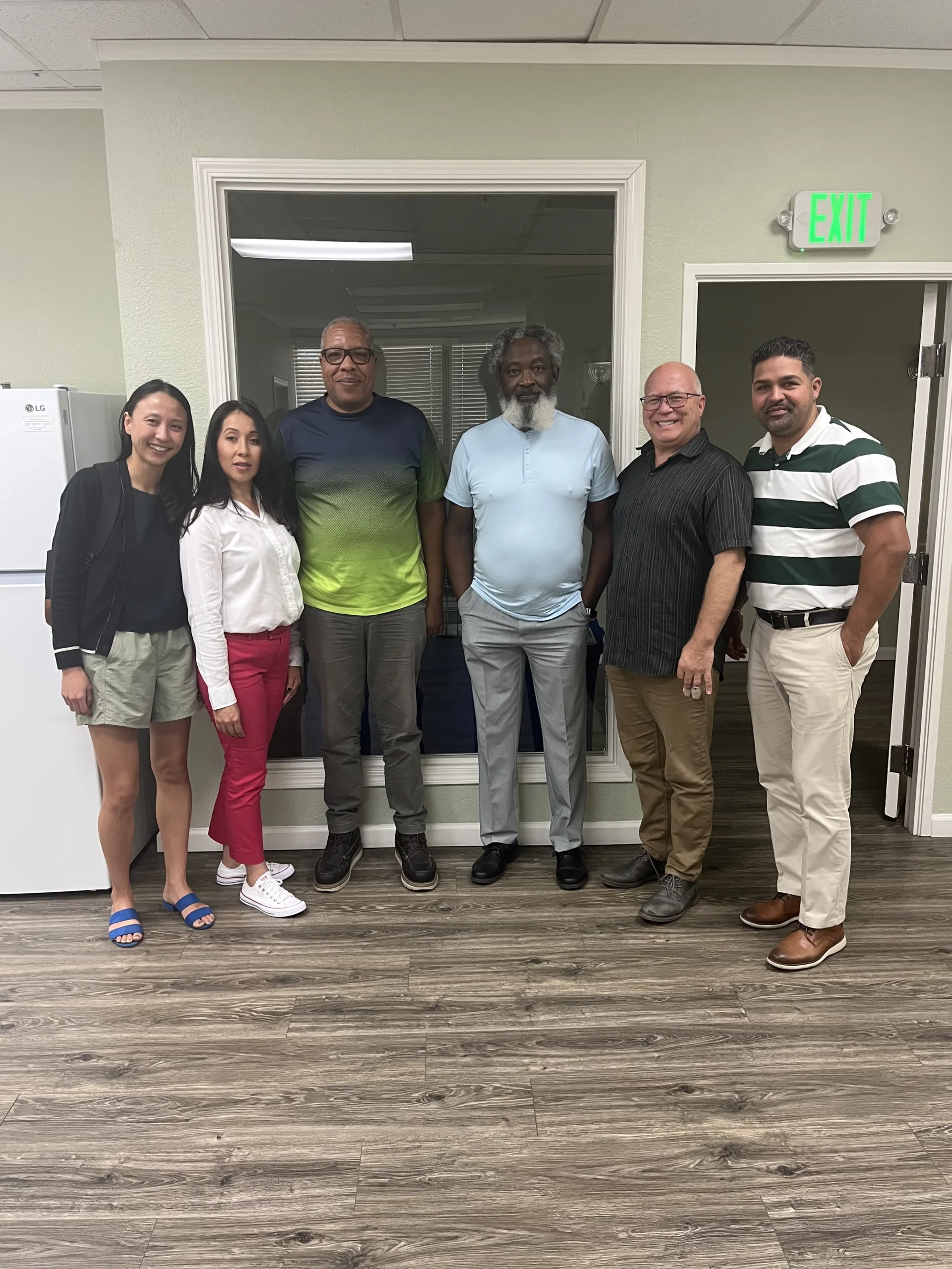 A group of six people posing for a photo in an office setting.